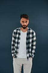 Wall Mural - In a checkered shirt. Handsome man is in the studio against blue background