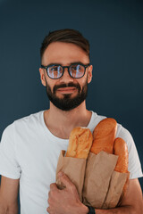 Wall Mural - Baguette, meal. Handsome man is in the studio against blue background