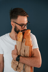 Wall Mural - Baguette, meal. Handsome man is in the studio against blue background