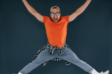 Wall Mural - Jumping, feeling good, excited. Handsome man is in the studio against blue background