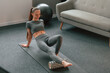Leg are on the foam roller. Young woman in yoga clothes doing fitness indoors