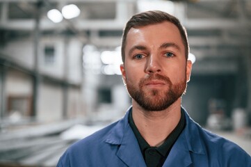 Portrait of factory worker that is in blue uniform indoors