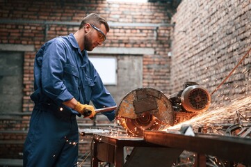 Wall Mural - Many of the sparks. Welding the metal. Factory worker in blue uniform is indoors