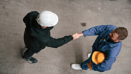 Wall Mural - Two industrial workers are doing handshake. Top view. Successful agreement