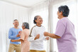 Active Asian senior group mix with man and woman exercise by dancing together with relaxing, smiling and laughing. Indoor activity for mature seniors and retirement people. Focus on senior woman.