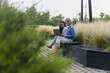 © EFStock - Female coworkers working on laptop sitting outside business corporate office building