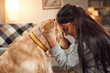 © standret - Side view. Having fun, embracing. Woman is with golden retriever dog at home