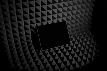 Wall Mural - Tablet mockup template on a black soundproof foam background with deep shadows, real photo. Blank isolated to place your design. 