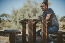 Smiling Man Sitting On A Picnic Bench Under A Pergola, Albufera, Valencia, Spain