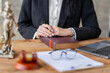 © crizzystudio - Professional Asian female lawyer or legal advisor sitting at her desk holding hands on books on justice concept Sections in the law that govern the conduct.