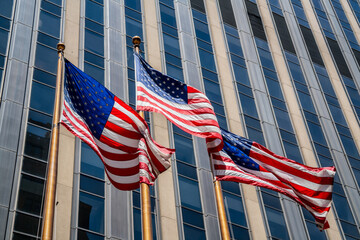 Big American flags waving in the wind of freedom on golden poles