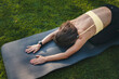© Strelciuc - Top view of a sporty woman streching her back before more advansed exersices, sitting on yoga mat in open air. Sun glare effect. Happy lifestyle. Healthy