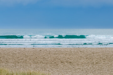 Poster - Sun illuminates sand beach under dark cloud.