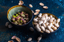 A Bowl Of Pistachio Nuts In Shells Next To A Bowl Of Shelled Pistachios