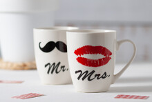 Two White Cups That Together Form A Pair. One Shows A Woman's Red Lips, And The Other A Man's Black Mustache. Good Mood For Valentine's Day