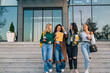 © cherryandbees - Front view of four college students walking out the college building