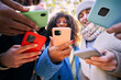 © CarlosBarquero - Low angle view of a group of young teenagers friends using mobile cell. Millennial people addicted to technology. Social Media communication generation Z. Selective focus on phone