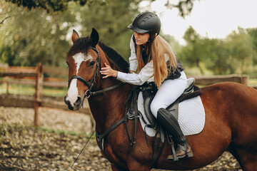 A young female jockey is sitting on her horse in show jumping training. Preparing for the competition.