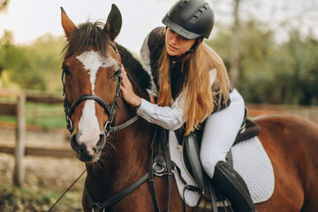 A young female jockey is sitting on her horse in show jumping training. Preparing for the competition.