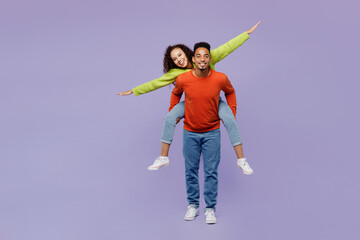 Wall Mural - Full body young couple two friends family man woman of African American ethnicity wear casual clothes together giving piggyback ride to joyful, sit on back isolated on plain light purple background.