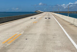 Travel in Florida by car, beautiful view of long Overseas Highway with cars, ocean water of Gulf of Mexico and power pylons on both sides of the road,