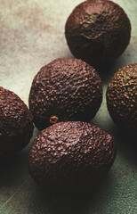 Wall Mural - Ripe brown avocado on rusty green kitchen table background, top view