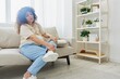 © SHOTPRIME STUDIO - Pregnant woman sitting on sofa at home and putting on pregnancy-friendly shoes with problem due to belly, headache, difficulties of pregnancy and motherhood