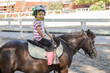 © ideasRojas  - Beautiful interracial little girl on a pony posing with confidence for a picture at ranch. Copy space.