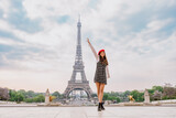 Fototapeta Paryż - Beautiful young woman visiting paris and the eiffel tower. Parisian girl with red hat and fashionable clothes having fun in the city center and landmarks area