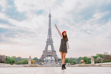 Beautiful Young Woman Visiting Paris And The Eiffel Tower. Parisian Girl With Red Hat And Fashionable Clothes Having Fun In The City Center And Landmarks Area