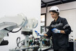 © amorn - Female engineer control autonomous mobile robot or AMR in the manufacturing automation and robotics academy room. Woman engineer training or maintenance AI robot