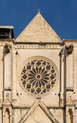 Wall Mural - Detail vertical view of ancient St Roch church stone facade with rosette in bright sunlight, Montpellier, France