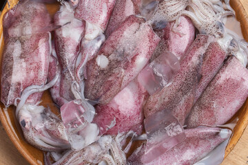 Fresh raw squids with ice and parsley on gray table, flat lay. On wooden background.