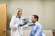 © Sean Locke/Stocksy - Clinic: Doctor Using Ophthalmoscope To Check Patient