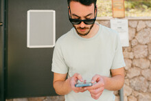 Bearded Man With Sunglasses Checking His Smartphone In The Street