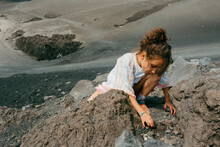 Curious Kid Collecting Rocks In Mount Etna Volcano Crater In Sunny Day