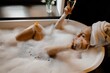 © Vladimir Tsarkov/Stocksy - Woman chilling in bubble foam bathtub with champagne