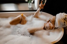 Woman Chilling In Bubble Foam Bathtub With Champagne 
