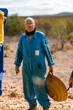 © Ezequiel Giménez/Stocksy - Elderly man with basket standing in farmyard