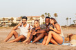 © Pedro Merino/Stocksy - Young adult friends drinking beer on the beach