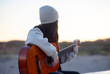Young Girl On The Beach Playing The Guitar
