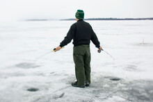 An Ice Fisherman Uses Two Poles To Fish In Maine.