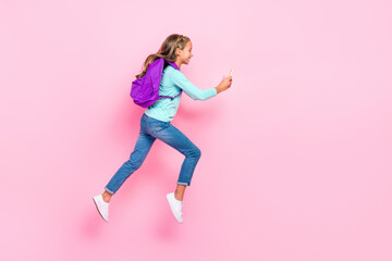 Poster - Full size profile portrait of beautiful little girl jumping hurry run use telephone isolated on pink color background