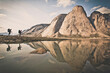 © Cavan Images - Silhouetted reflection of two backpackers opposite mountain landscape.