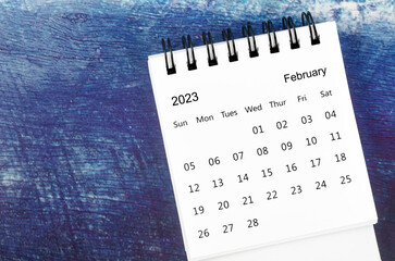 The February 2023 Monthly desk calendar for 2023 year on old blue wooden background.