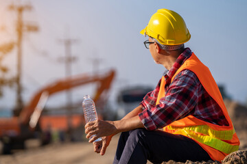 Male engineer takes a break to drink water to relax in the sweltering midday heat.