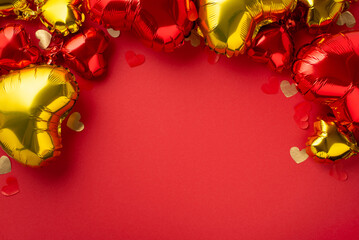 Wall Mural - St Valentine's Day concept. Top view photo of heart shaped red yellow balloons and confetti on isolated red background with empty space