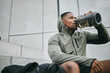 © Siphosethu/peopleimages.com - Fitness, relax or black man drinking water in training or exercise for body recovery or workout in Chicago, USA. Hydration, thirsty or tired healthy sports athlete drinks natural liquid in bottle