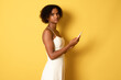 © Danko - Content smiling woman with afro hairstyle typing text message or using internet on smartphone isolated over yellow background