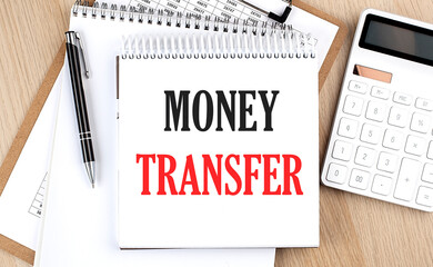 Poster - MONEY TRANSFER is written in white notepad near a calculator, clipboard and pen. Business concept